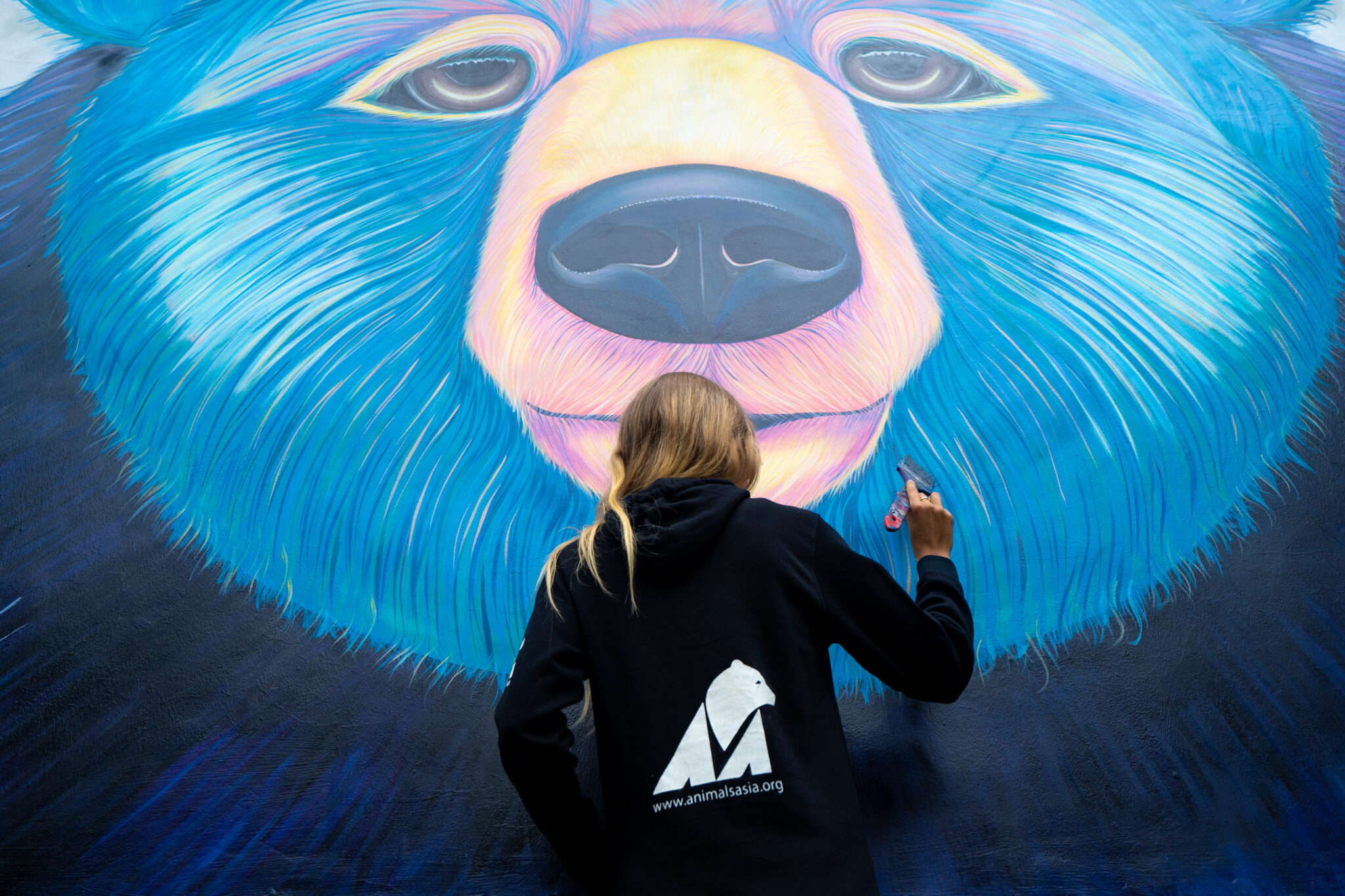 Ekaterina Sky painting a bear mural for Animals Asia in Vietnam, Animalize World Mural Tour