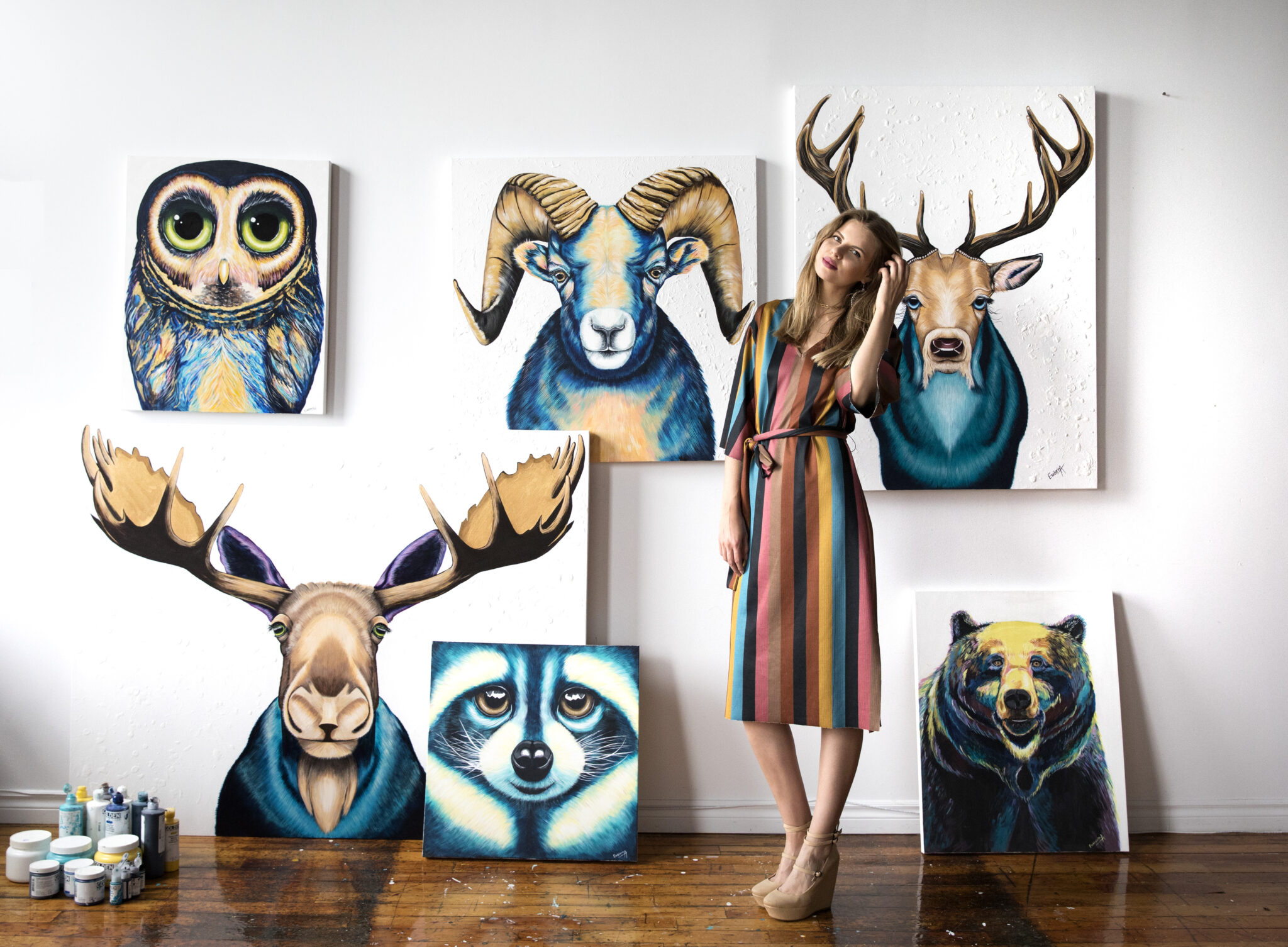 Ekaterina Sky in the studio with Canadian Animalize paintings of an owl, ram, deer, moose, raccoon and bear